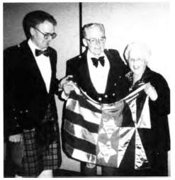 Hugh Moore and Marian Moore with their eldest son Michael Moore hold the heraldic banner